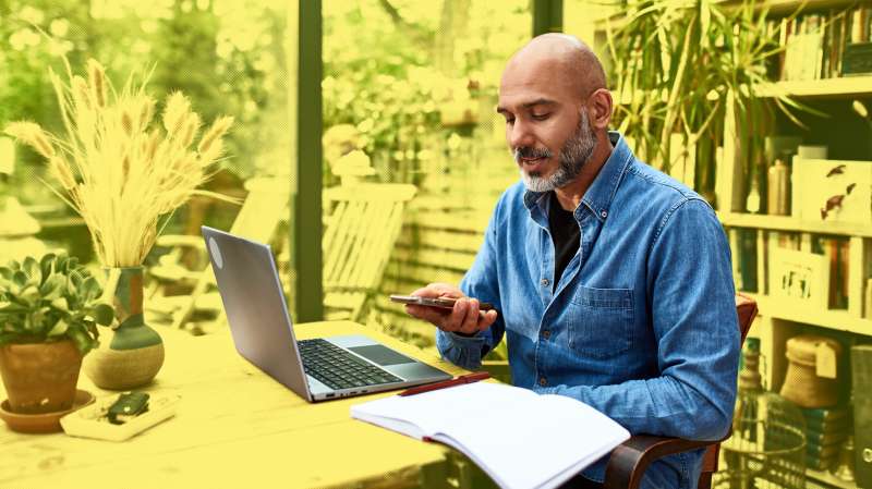 Mature man talking on his mobile phone, while working from home