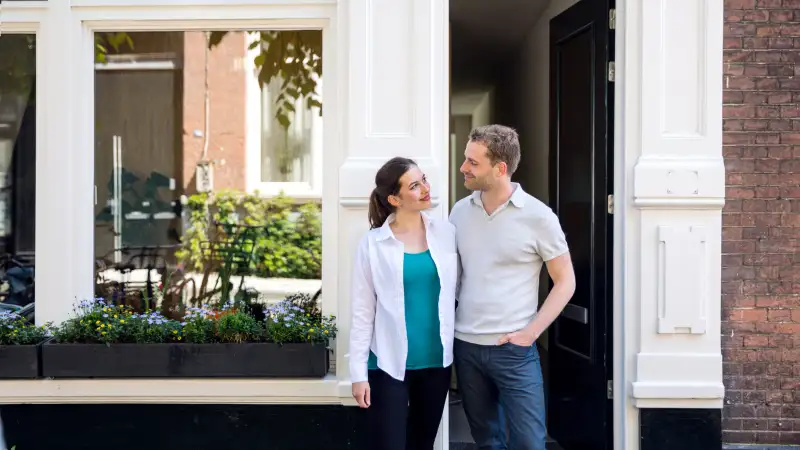 Lovely couple standing in front of their new house