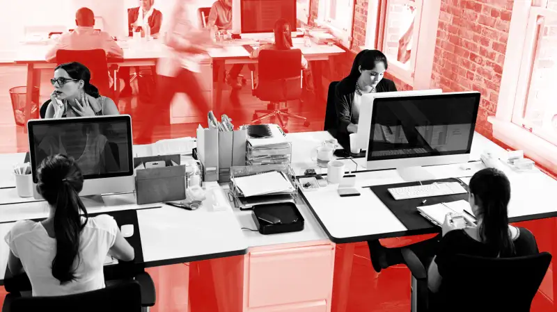 Photo of a busy office with multiple employees working from their desks