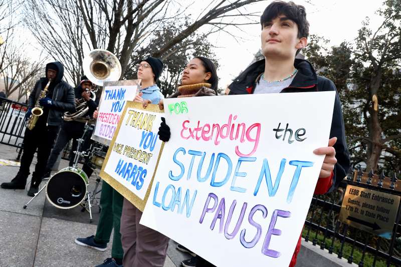 A group of people holding signs thanking President Biden and Vice President Harris for extending the student loan pause once again