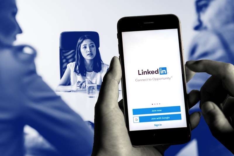 Collage of a hand holding a smartphone with the LinkedIn logo and an image of two people interviewing a potential candidate in the background