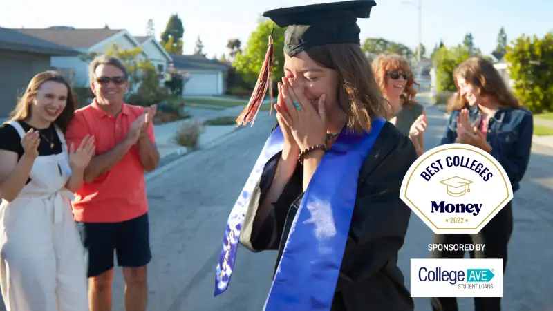 A student wearing a cap and gown with her family on graduation day