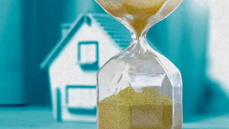 Photo illustration of an hourglass and a house in the background