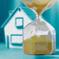 Photo illustration of an hourglass and a house in the background
