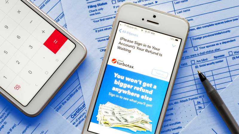 Close-up of a smartphone with the Turbo Tax App open and a 1040 Tax Form in the background