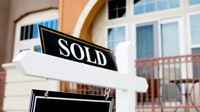 Close-up of a Sold sign in-front of a house