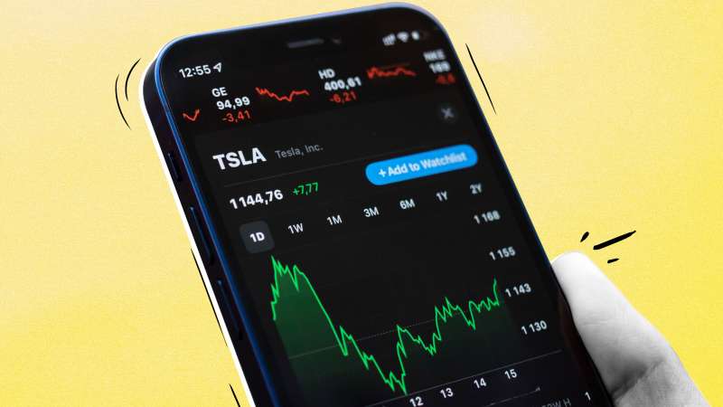 Close-up of a hand holding a smartphone looking at Tesla Stock