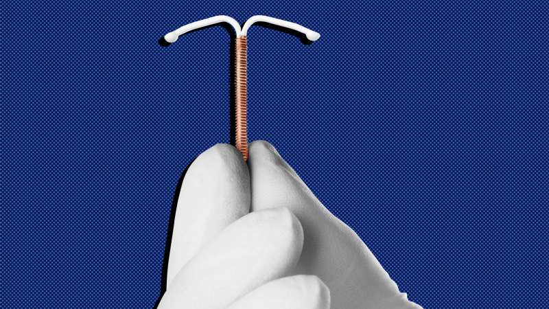 Close up of a gloved hand holding an IUD device