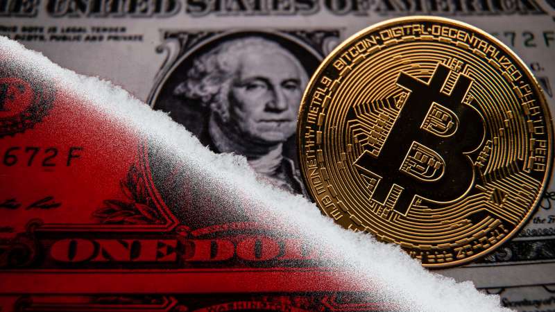 photo illustration of a bitcoin coin rolling downhilll atop an image of a US Dollar
