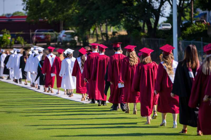 Students walk in cap and gown in a graduation ceremony