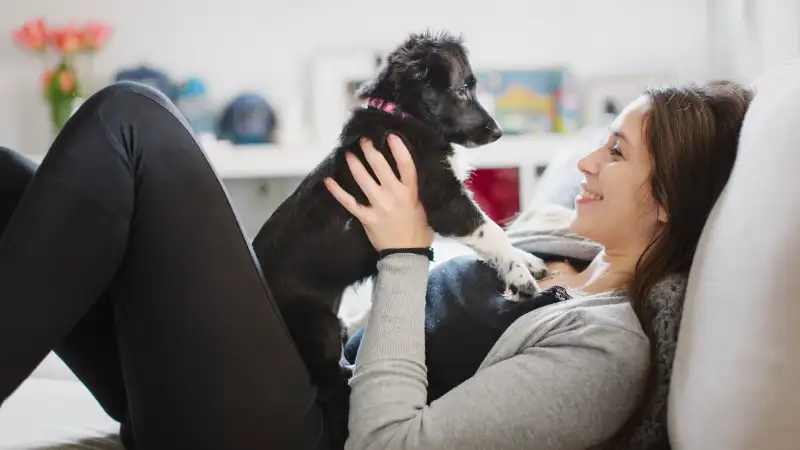 Photo of a smiling young woman and her cute puppy dog