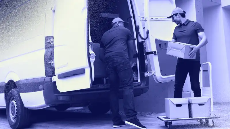 Photo of two men moving boxes and furniture