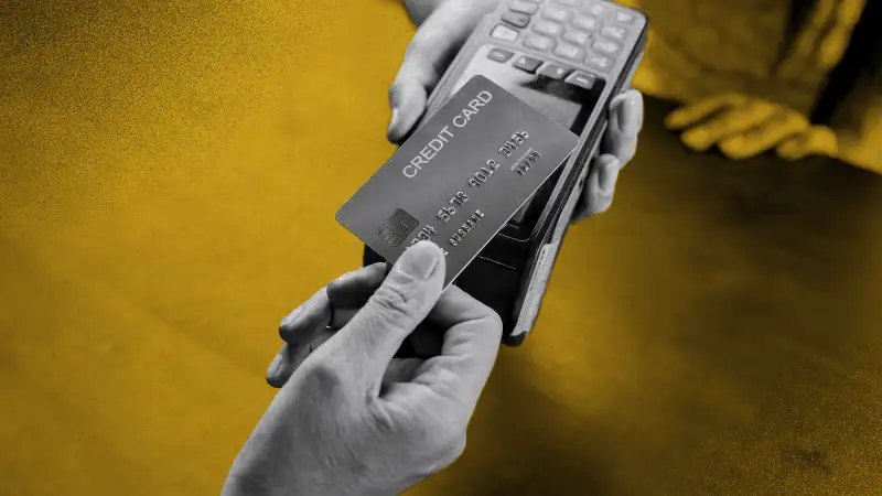 Close up of a hand presenting a credit card on a point of purchase machine