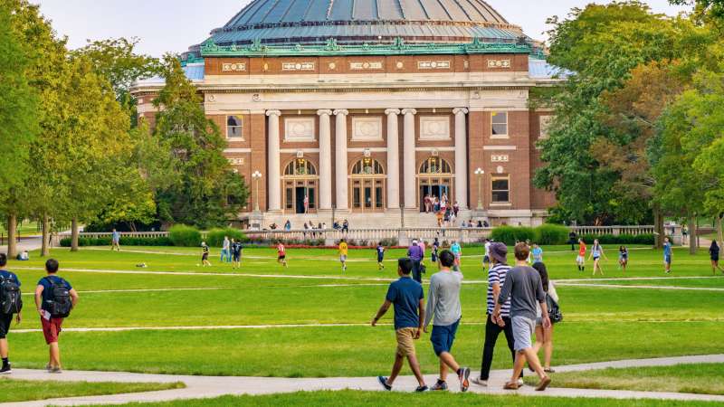 Students walk outdoors on lawn of University campus