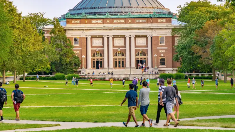 Students walk outdoors on lawn of University campus