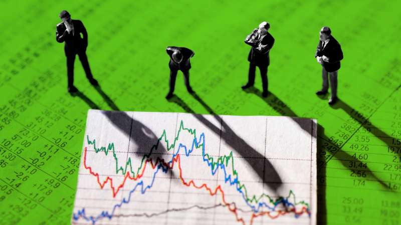 Photo collage of businessmen figurines looking at a stock market chart