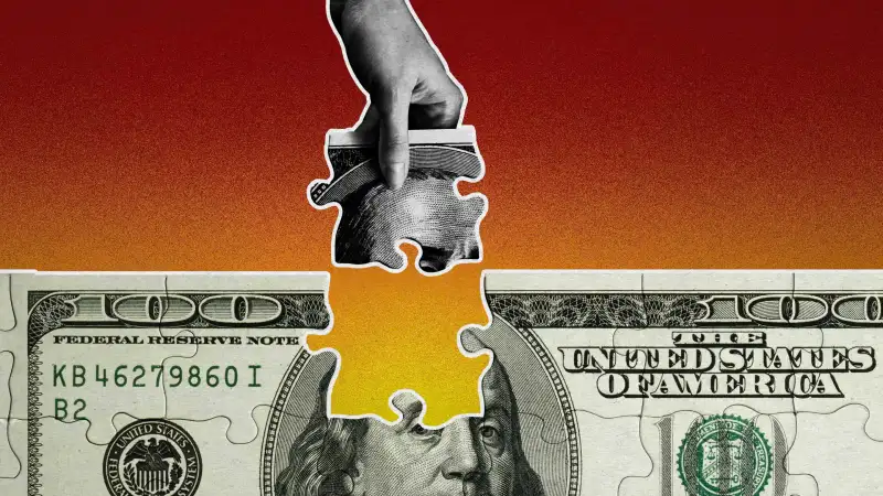 Photo illustration of a hundred dollar bill puzzle and a hand with the missing piece