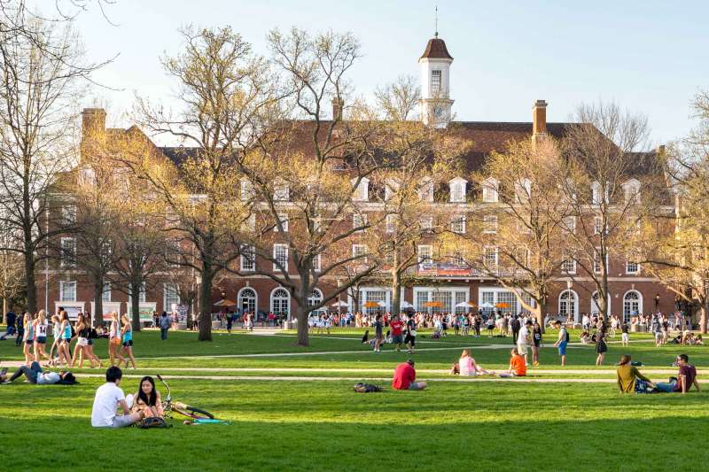 A College Campus With Students Sitting On The Grass