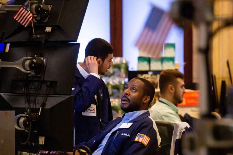 Stock Trader Looking Up At Screens At NYC Stock Exchange