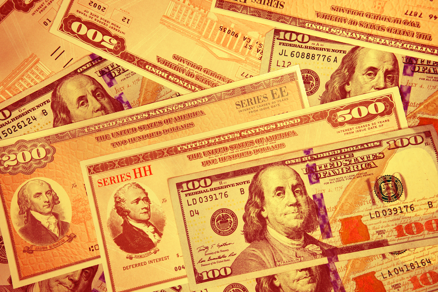 eries HH and Series EE United States Treasury Savings Bonds surrounded by US currency in cluding a $100 bill