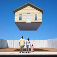 Composite of a family of three looking up at a house for sale, floating above an empty lot
