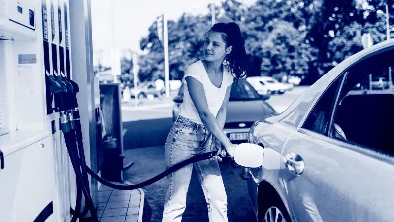 A young woman refueling the gas tank of her car