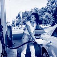 A young woman refueling the gas tank of her car