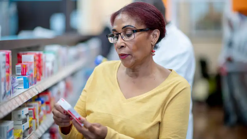 Elderly woman examining the costs of the medicines she's about to buy