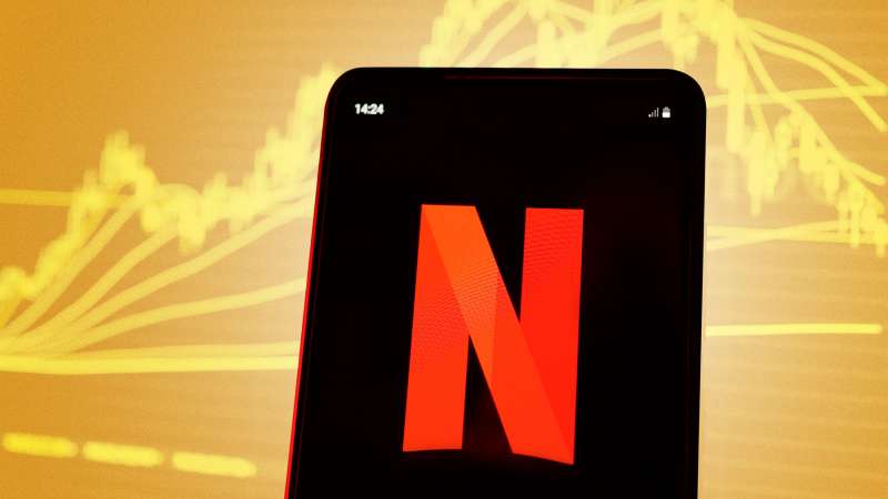 Smartphone showing the Netflix logo with a stock chart in the background