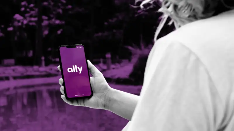 Close-up of a person holding a smartphone with the Ally bank app