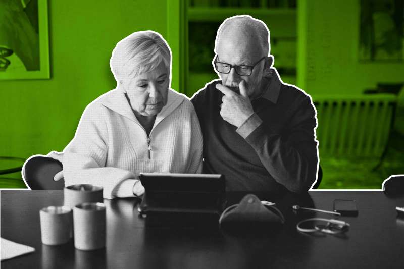 Senior couple using digital tablet while sitting by dining table in living room