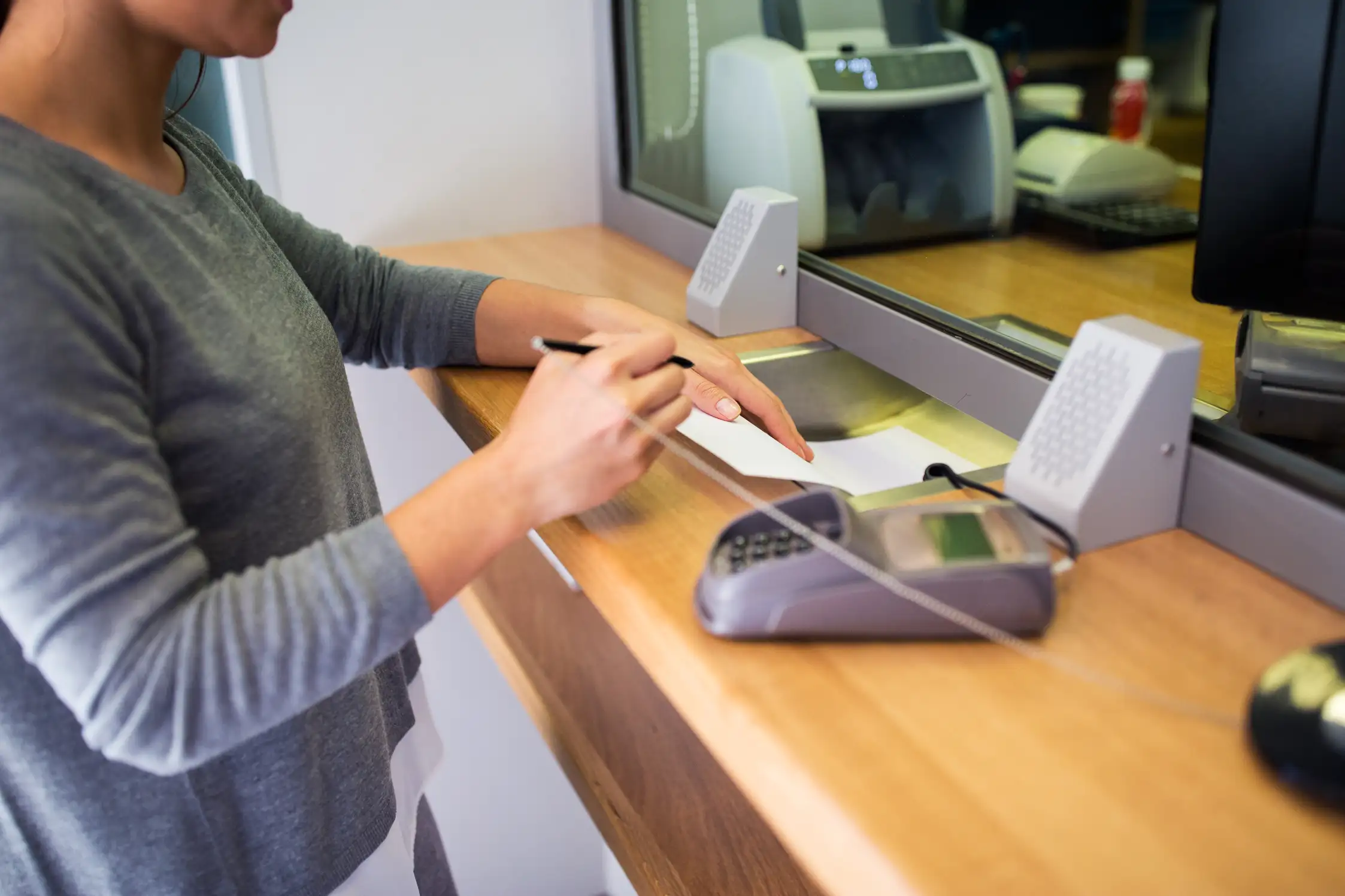 Customer with pen and paper writing application at bank office