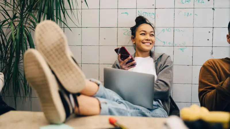 young businesswoman sitting with feet up on desk using a cellphone