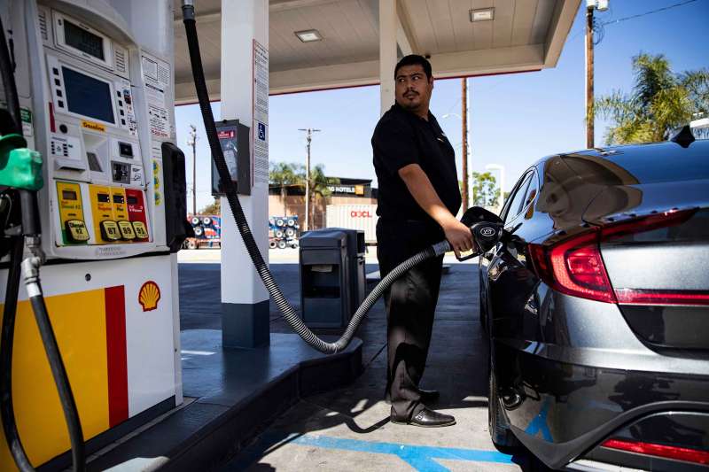 A man looks at the screen displaying the prices as he refuels his car at gas station