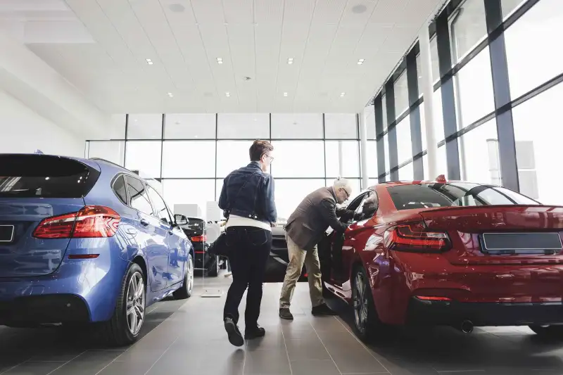 Senior man and woman examining car at showroom