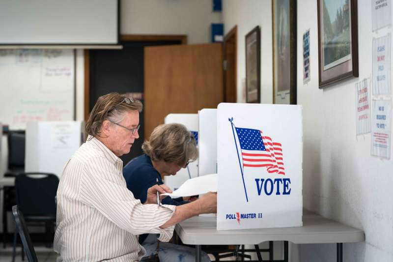 A person fills out a ballot at a voting booth