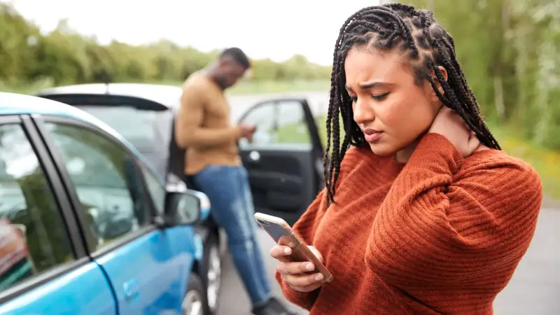 A woman placing a phone call to insurance company after being in a car accident