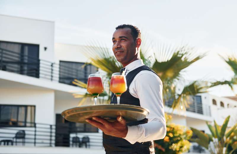 Waiter carrying multiple cocktail drinks on a traya