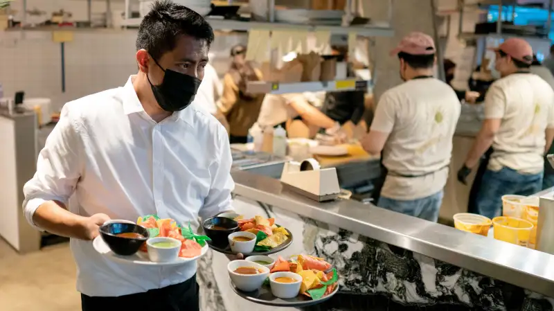 A waiter carries three plates from the kitchen at a Mexican Restaurant