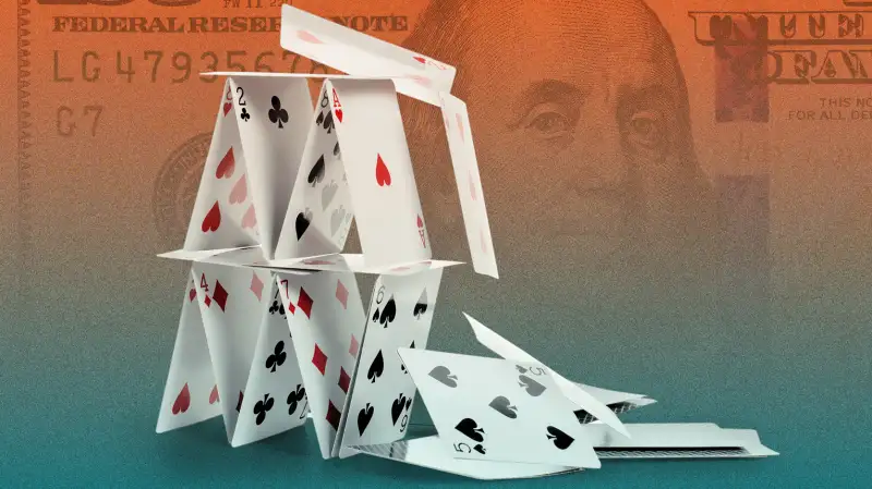 Photo collage of a falling house of cards with a hundred dollar bill in the background