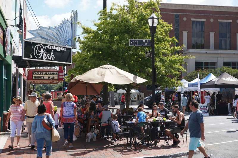 People enjoying a sunny day, eating outdoors, people watching during an outdoor festival and open air market in Marietta, Georgia