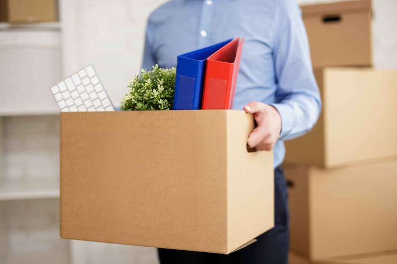 Close up of male hands holding cardboard box with office things