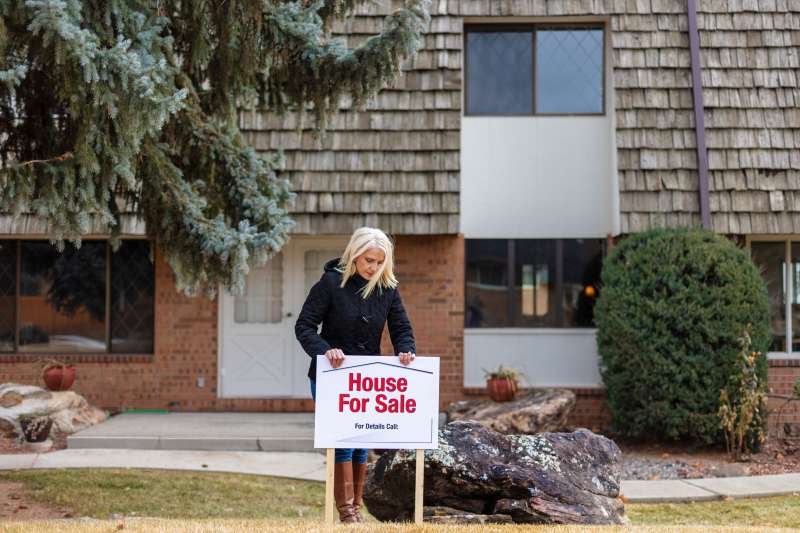 Real estate agent setting up a  House For Sale  sign in-front of a property