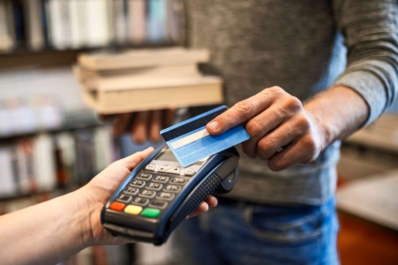 Close-up of a man paying books with a credit card