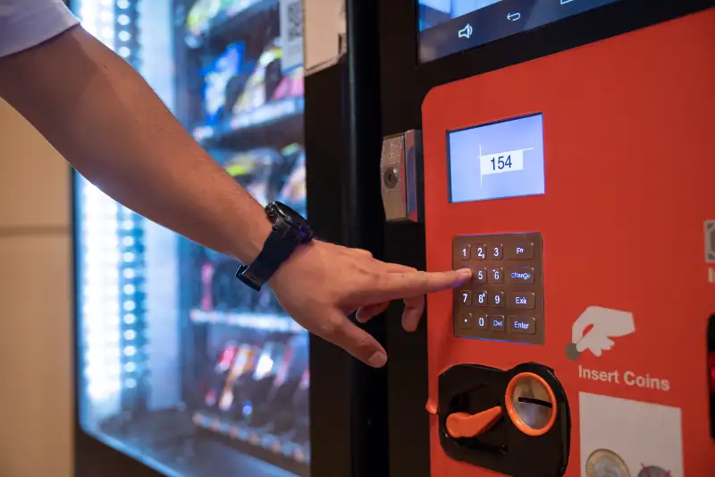 Man's hand pressing buttons on a vending machine