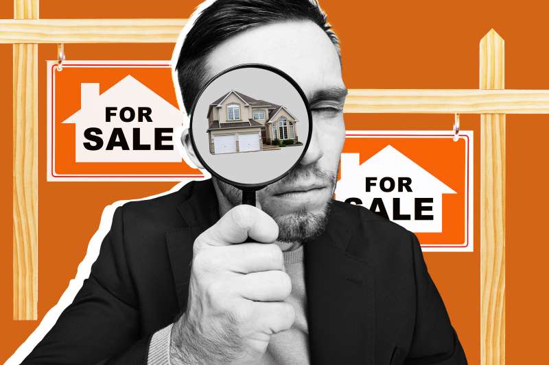 Man holding magnifying glass with house inside glass with for sale signs in background