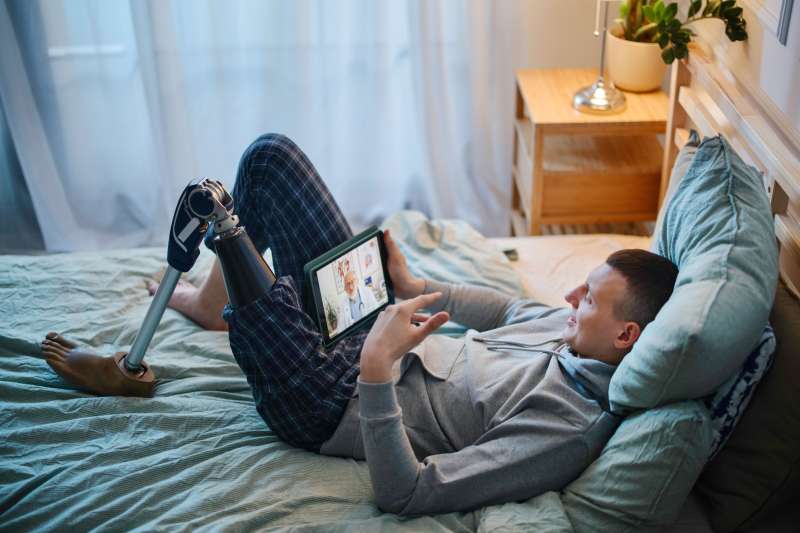 Disabled young man with prosthetic leg having online session with a doctor