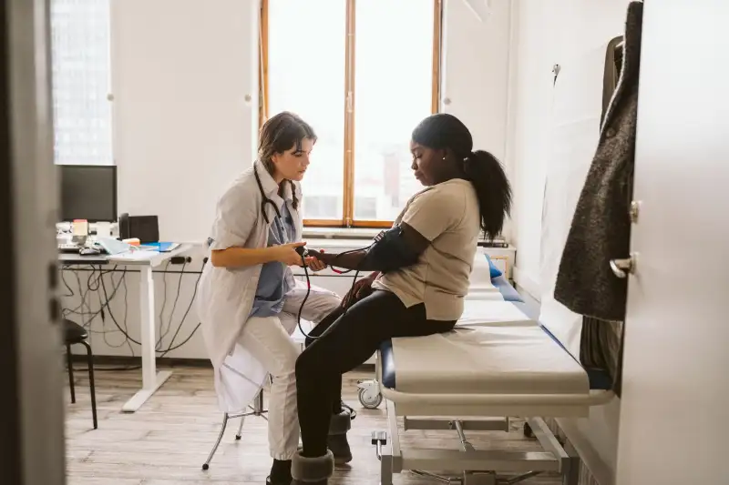 Female healthcare worker measuring young patient's blood pressure in medical clinic