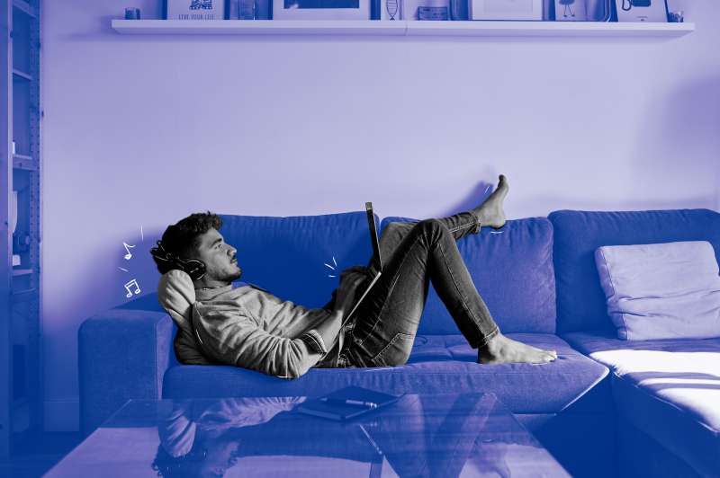 Man laying down on his couch working from home on his laptop