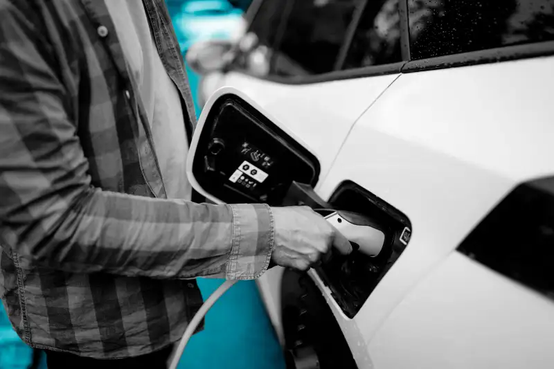 Close-up of a man plugging charger in electric car